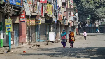 People walk past closed shops at market amid curfew at Banbhoolpura area 