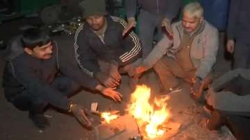 People sit near a bonfire to warm themselves in Delhi's Chandani Chowk.