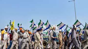 Farmers holding flags march during their ongoing protest over various demands, including a legal guarantee of minimum support price (MSP) for crops, at the Punjab-Haryana Shambhu Border.
