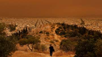 A man makes his way at a hill as African dust from the desert of Sahara covers the city of Athens