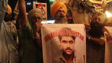 Indian Sikhs shout slogans against Pakistan as they display photographs of Sarabjit Singh, centre, w