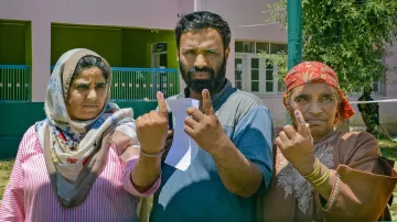 A family poses for photographs after casting votes at a polling station during the sixth phase of Lok Sabha elections, in Anantnag district of south Kashmir.