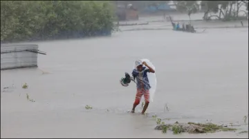 A boy wades through water during heavy rain amid Cyclone Remal in Bangladesh.