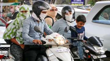 Commuters cover themselves for protection from the scorching sun on a hot summer day in Nagpur.