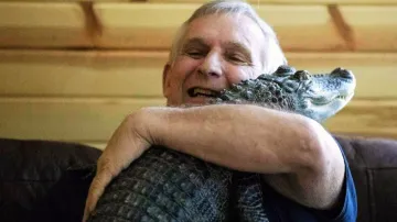 Joie Henney hugs his emotional support alligator named Wally inside their home in York Haven.