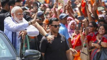 Prime Minister Narendra Modi waves at supporters during a roadshow, as part of campaign for Lok Sabha election 2024.