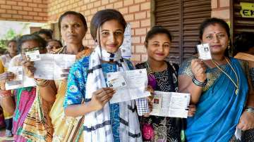 Voters show their identification cards as they wait in a queue at a polling station to cast their votes for the fourth phase of Lok Sabha elections.