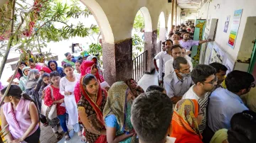 People wait in a queue to cast vote at a polling station under East Delhi constituency during the sixth phase of Lok Sabha elections, in New Delhi.