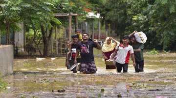 People wade through a flooded area in Assam