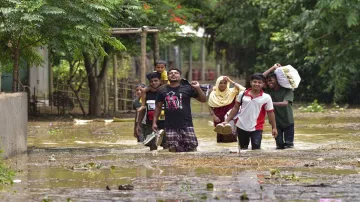 People wade through a flooded area in Assam