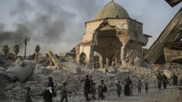 Fleeing Iraqi civilians walk past the heavily damaged al-Nuri mosque as Iraqi forces continue their 