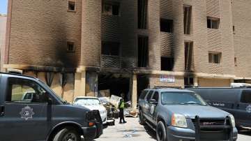 A Kuwaiti police officer is seen in front of a burnt building following a deadly fire, in Mangaf, so