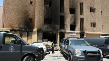 A Kuwaiti police officer is seen in front of a burnt building following a deadly fire, in Mangaf, so