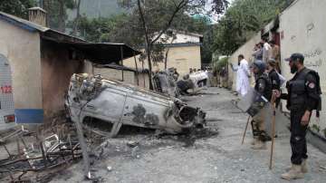 Police officers examine burnt vehicles which were torched by a Muslim mob in an attack, in Madyan.
