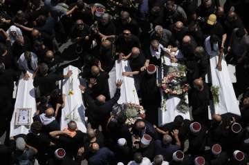 Mourners from the Druze minority surround the bodies of some of the 12 children and teens killed in a rocket strike at a soccer field, in the village of Majdal Shams