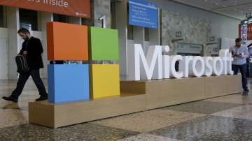 A man walks past a Microsoft sign set up.