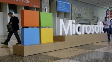 A man walks past a Microsoft sign set up.