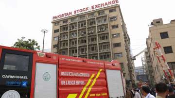 People gather as firemen work after a fire broke out in the Pakistan Stock Exchange building in Karachi
