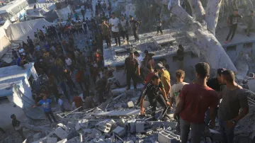 Palestinians search for bodies and survivors in the rubble of a residential building destroyed in an Israeli airstrike in Khan Younis