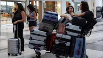 Women stand near their luggage in front of the Middle East Airlines (MEA) offices at the Beirut–Rafi