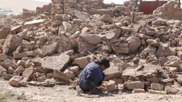  boy cries as he sits next to debris, in the aftermath of an earthquake in the district of Zinda Jan