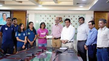 Jalal Yunus (in centre) presenting a cheque to football team captain Sabina Khatun (on left)