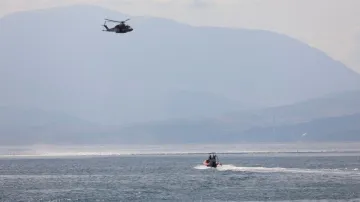 Emergency and rescue services work near the scene where a sailboat sank in the early hours of Monday