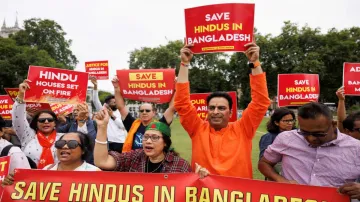 People hold signs at a protest against violence targeting Bangladesh's minority Hindus, after former