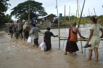 Local residents wade through flooded water at a broken bridge, in Naypyitaw, Myanmar.