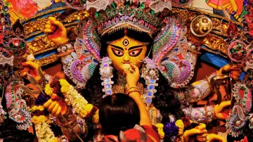 A devotee offers sweets to an idol of the Hindu goddess Durga while offering prayers on the last day