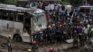 People stranded at the Tribhuwan Highway look on as rescue personnel work to retrieve the bodies of the victims from a landslide triggered by heavy rainfall in Dhading, Nepal.