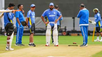 Rohit Shara, along with the head coach and other players looking ta  the surface at M Chinnaswamy Stadium