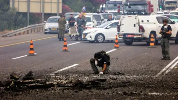 A security official handles the remains of a rocket that landed on a highway after it was fired from Lebanon into Israel.