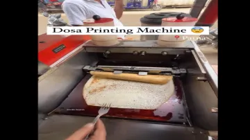 The video shows a printer machine in use to make dosa