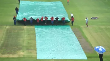 Groundstaff rushes to cover the pitch at St. George's Park in Gqeberha.