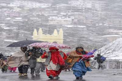 People walk amidst fresh snowfall at the Ridge in Shimla, Wednesday, Dec 12, 2018.