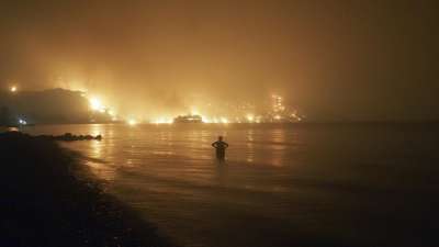 A man watches the flames as a wildfire approaches Kochyli beach near Limni village on the island of Evia, about 160 kilometers north of Athens, Greece.