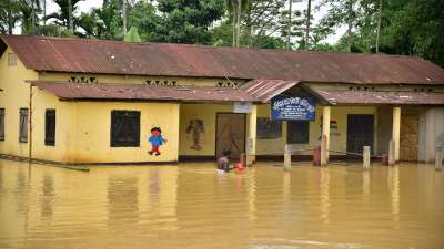 A man wades through a partially submerged school in a flood-affected area, following heavy rains in Hojai district of Assam.&amp;nbsp;