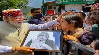Prime Minister Narendra Modi stops to accept a painting from a young woman during a roadshow in Shimla.