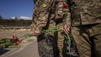Irpin Territorial Defence and Ukrainian Army soldiers hold flowers to be placed on the graves of fallen comrades during the Russian occupation, at the cemetery of Irpin, on the outskirts of Kyiv, on Sunday, May 1, 2022.&amp;nbsp;