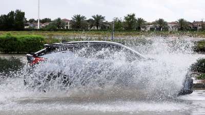 An SUV drives through floodwater covering a road in Dubai