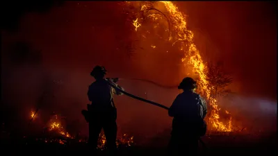 Firefighters using a hose to douse a burning hillside in Los Angeles.