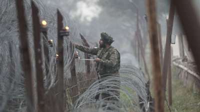 An Indian army soldier lights an earthen lamp on a fence to celebrate Diwali, near the Line of Control in the Akhnoor sector of Jammu and Kashmir