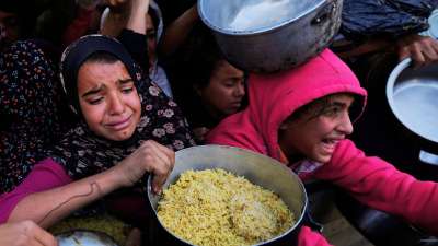 Palestinian girls struggle to reach for food at a distribution center in Khan Younis, Gaza Strip Friday, Dec. 6, 2024