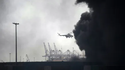 A helicopter flies above the smoke following an explosion