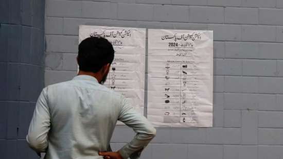 India Tv - A voter seeing the candidate list in Karachi