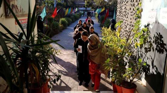 India Tv - The voters enter a polling station in a school on 