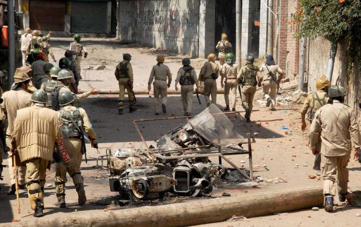 Security personnel chasing away stone throwing youth in