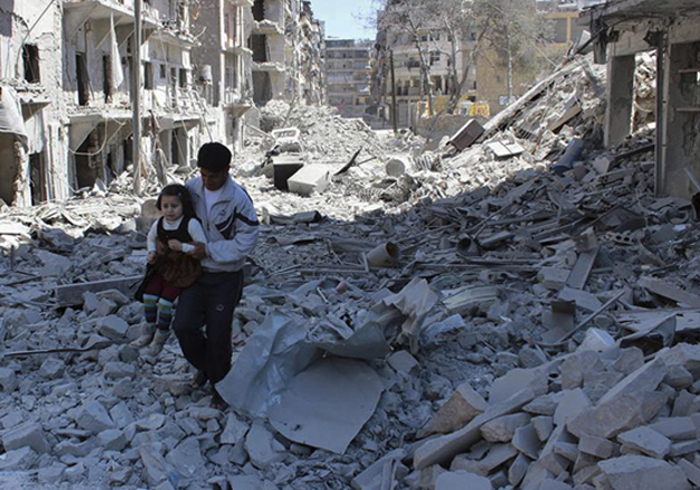 A Syrian man holding a girl as he stands on the rubble of