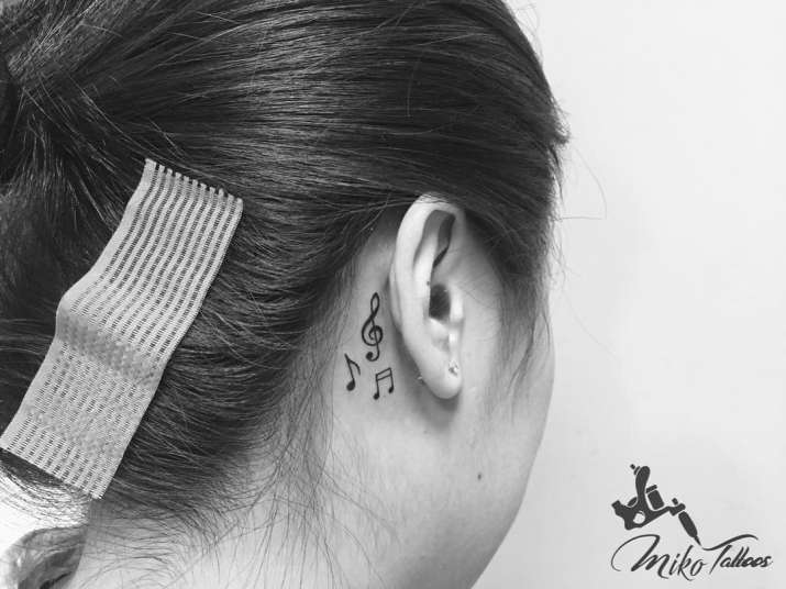 Tiny music note tattoos on the left ear